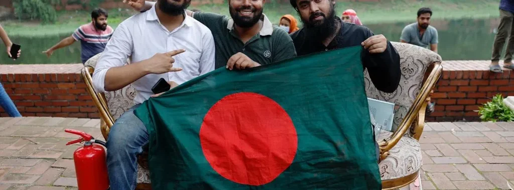 Des manifestants posent avec le drapeau du Bangladesh sur un canapé pillé dans la résidence de la Première ministre. Photo: REUTERS